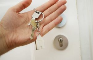 buying a property house keys in hand in front of a door