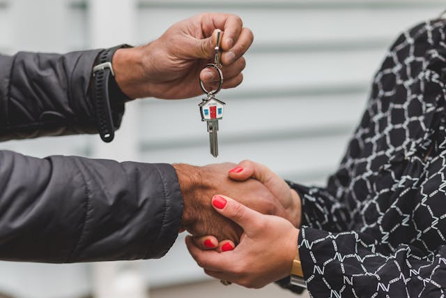 Person handing over house keys following mortgage completion - Assets For Life